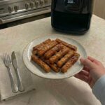 Air fryer basket being shaken halfway through cooking to evenly crisp carrot fries
