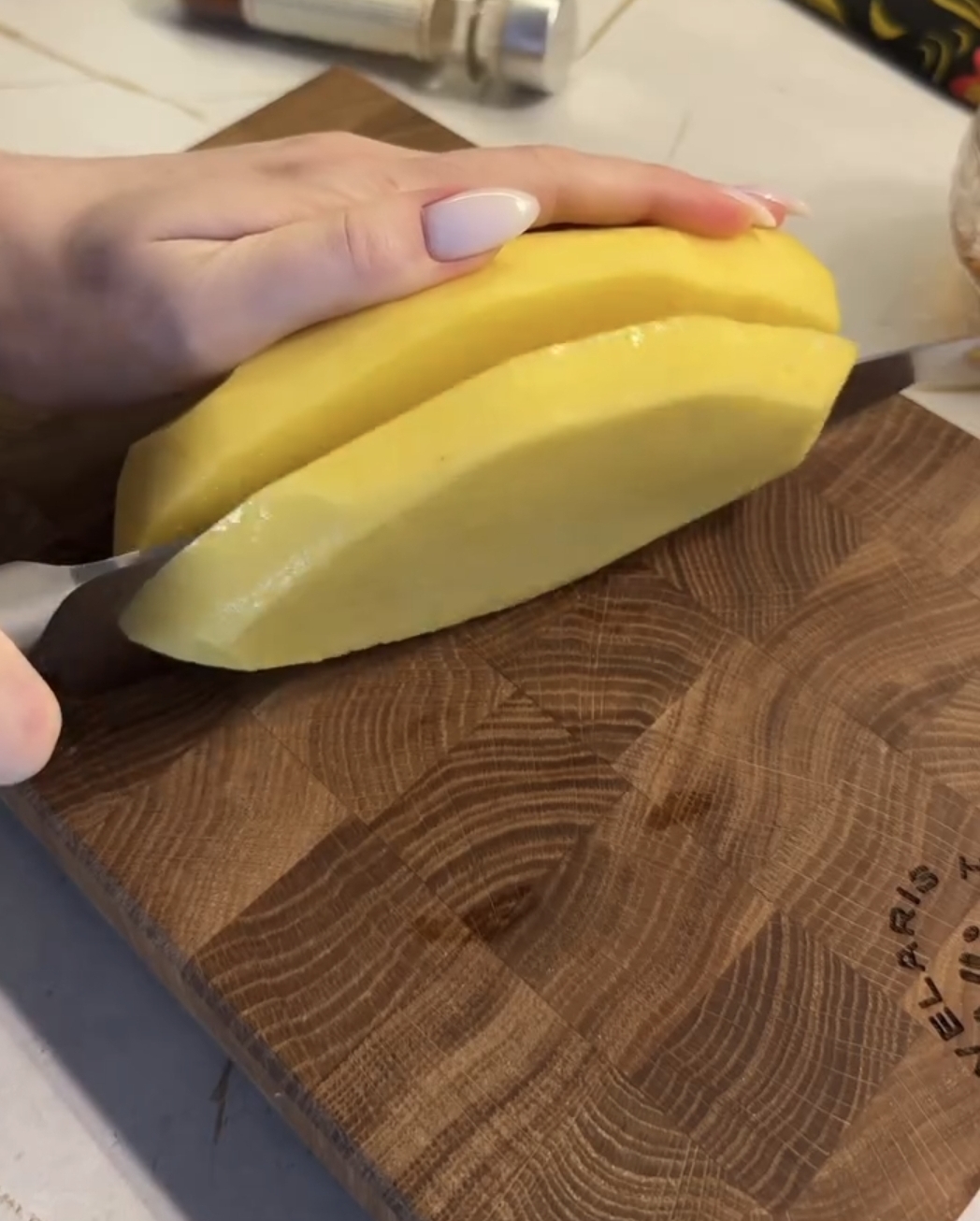 air fryer accordion potatoes being cut in half lengthwise on a wooden board