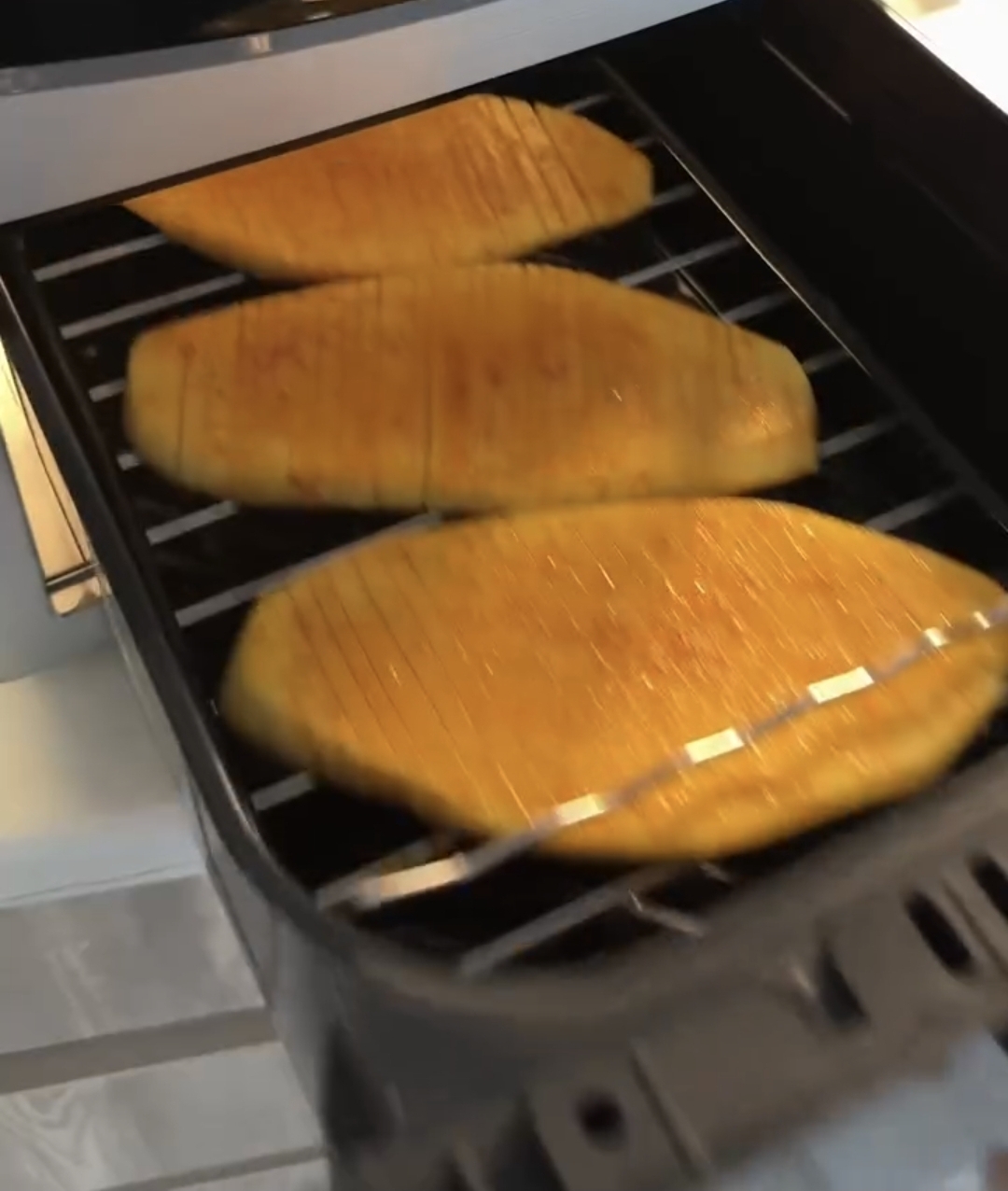 air fryer accordion potatoes arranged on the wire rack inside the air fryer basket