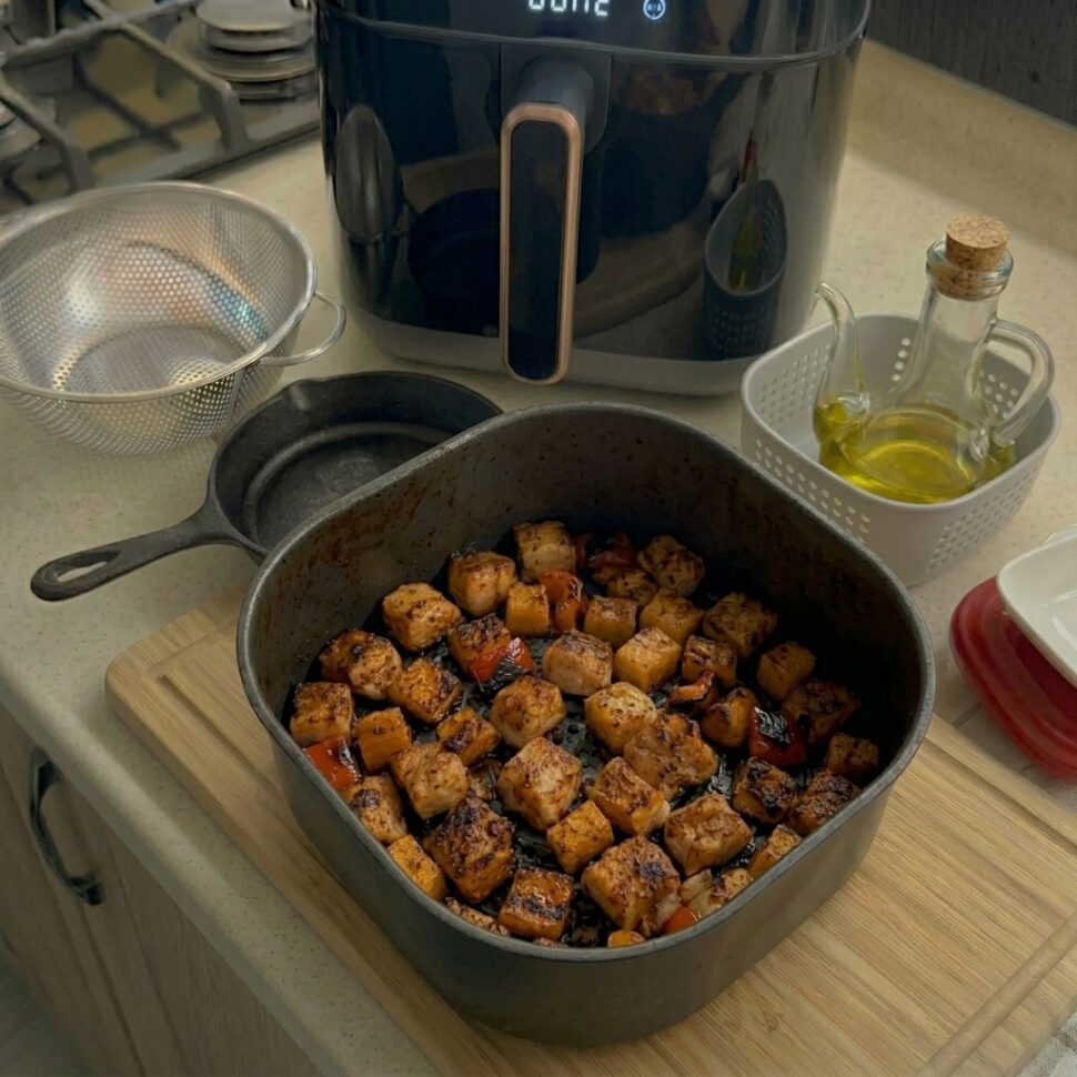 Air fryer basket being shaken halfway to evenly brown turkey meatballs