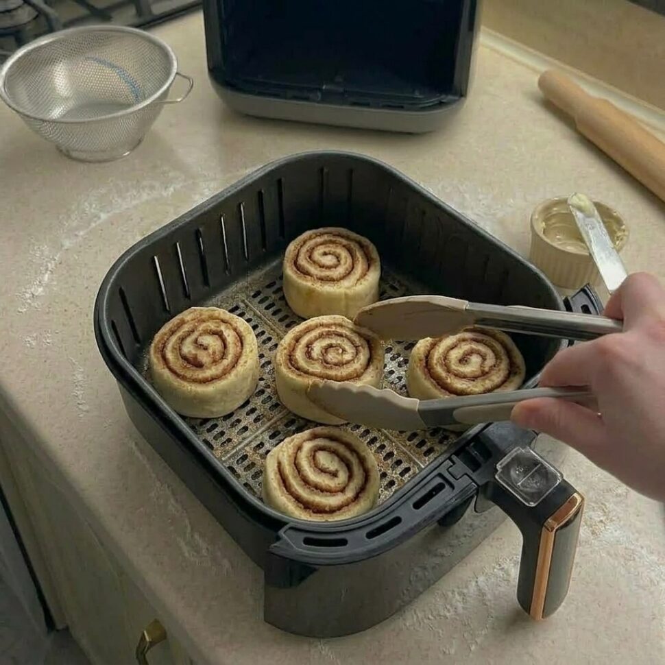 Cinnamon rolls baking in air fryer until golden and fluffy